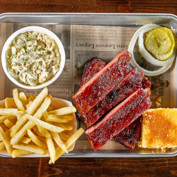 Gaskins Barbecue and Lobster's BBQ ribs, fries, coleslaw, cornbread, pickles, and onions on a tray.