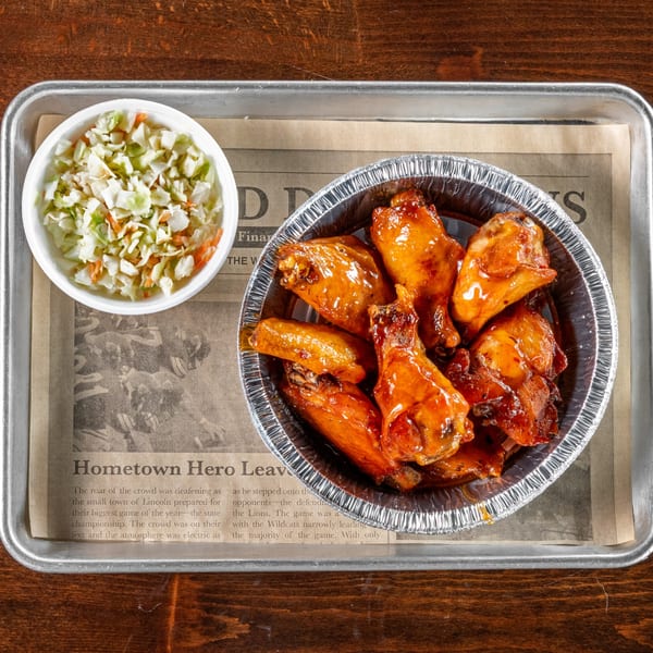 Gaskins Barbecue and Lobster's BBQ chicken wings in a foil container with a side of coleslaw.