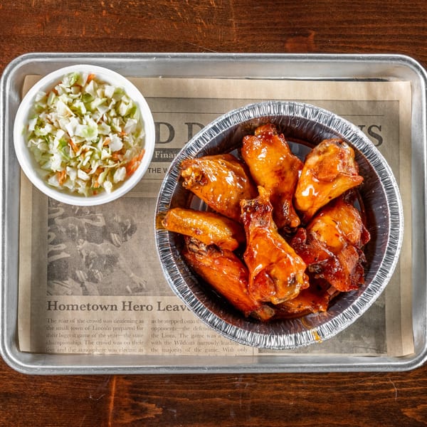 Gaskins Barbecue and Lobster's BBQ chicken wings in a foil container with a side of coleslaw.